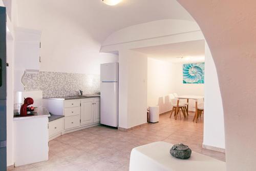 una cocina con armarios blancos y una mesa con sillas. en Gemini Cave Villa, en Oia