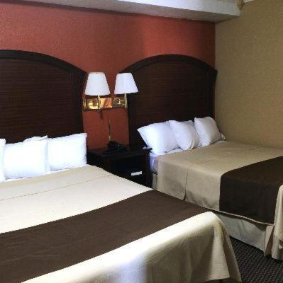 a hotel room with two beds and red walls at Americas Best Value Inn Schulenburg in Schulenburg