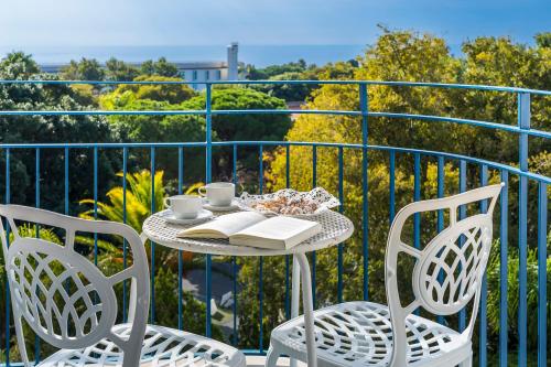 a table with two chairs and a book on a balcony at Sant Alphio Garden Hotel & SPA in Giardini Naxos