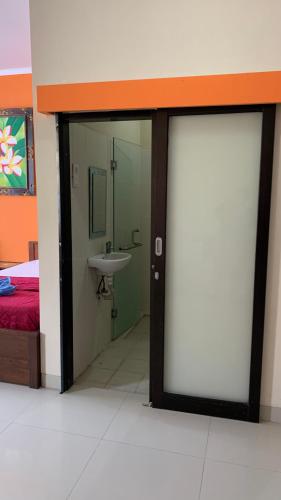 a bathroom with a sliding glass door with a sink at Taxa Uma Guest House in Kuta