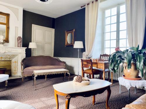 a living room with a bed and a table at Le Château de la Roque Hôtels in Hébécrevon