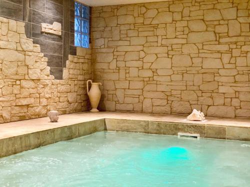 - une grande piscine d'eau dans une chambre dotée d'un mur en pierre dans l'établissement Le Château de la Roque Hôtels, à Hébécrevon