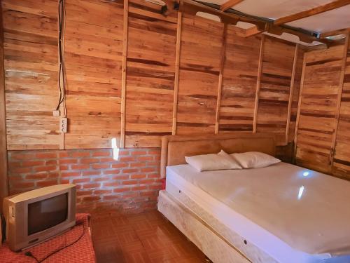 małą sypialnię z łóżkiem i telewizorem w obiekcie Family Guest House Lembang RedPartner w mieście Lembang