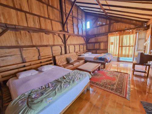 a room with three beds and a couch and a tv at Family Guest House Lembang RedPartner in Lembang