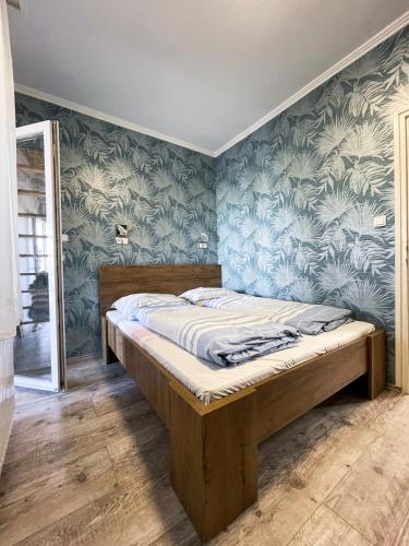 un letto in una stanza con carta da parati blu di Villa Klapka a Zamárdi