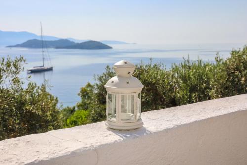 a glass jar sitting on a white railing with a boat in the water at Golden View Villa in Skiathos Town