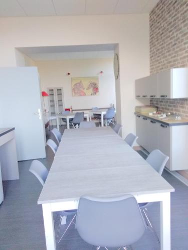 - une cuisine avec une table et des chaises blanches dans la chambre dans l'établissement La Maison Des Officiers, à Montier-en-Der