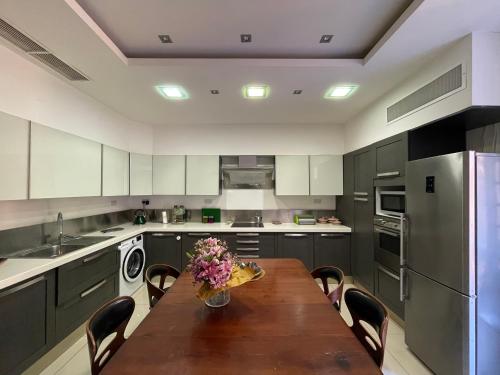 a kitchen with a wooden table with chairs and a refrigerator at Valletta Collection - Merchant Str Apartment with large yard in Valletta