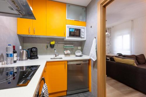 a small kitchen with yellow cabinets and a couch at Origen Sacramento Deluxe in Zaragoza