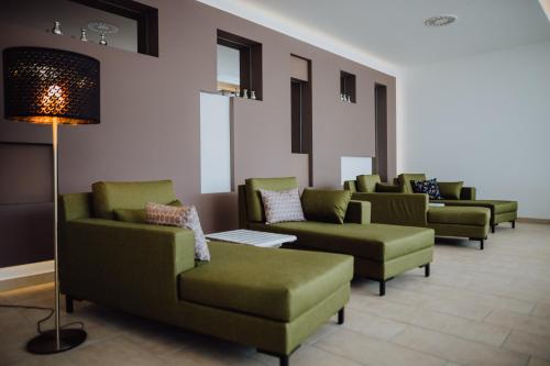 a waiting room with green couches and chairs at Alpenhotel Perner in Obertauern