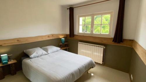 a bedroom with a white bed and a window at MAGNIFIQUE Location au bout de la route in Saint-Hilaire-les-Courbes
