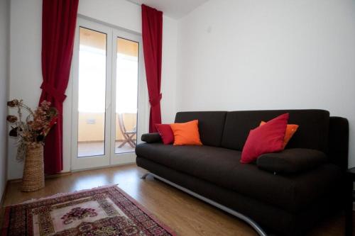 a living room with a black couch with red and orange pillows at Apartments Briest in Dubrovnik