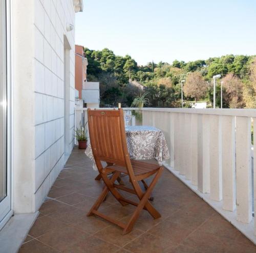 una silla de madera sentada en un balcón con una mesa en Apartments Briest, en Dubrovnik