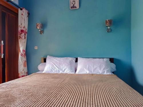 a blue bedroom with a bed with white pillows at Saung Aligo Syariah RedPartner in Cipondok