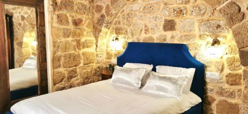 a bedroom with a bed with a blue headboard and a mirror at Stylish apartment with private parking by the marina in ‘Akko