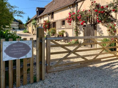 a wooden gate with a sign in front of a building at Le Bas Chesnay Gîte Domfront en Poiraie in Domfront