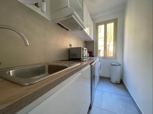 une cuisine avec un évier et un micro-ondes dans l'établissement Nice Renting - JAURES - Cosy Flat - Nice old town - Great view - AirCon, à Nice