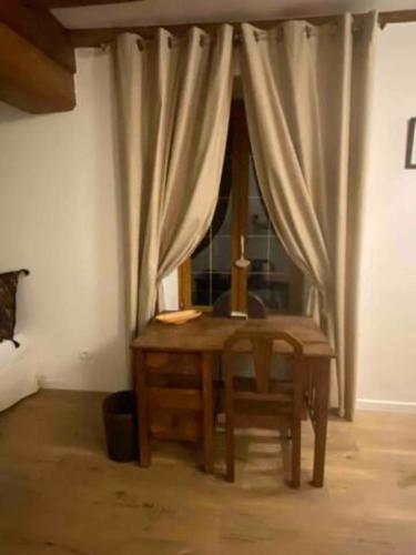 a wooden table and chair in a room with a window at Le Domaine de Moroges in Moroges