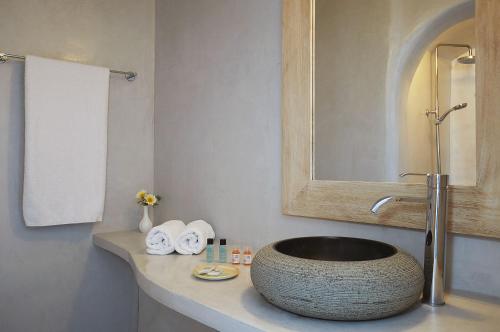 a bathroom with a sink with a mirror and towels at Finikia Memories Hotel in Oia