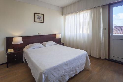 a hotel room with a bed and a dresser at Hotel Sete Cidades in Ponta Delgada