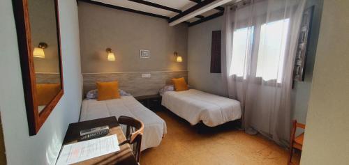 a small room with two beds and a window at Hotel Judería Valle del Jerte in Cabezuela del Valle