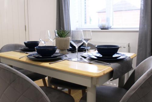 a wooden table with bowls and wine glasses on it at Abingdon - Private Flat with Garden & Parking 01 in Abingdon