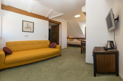 a living room with a yellow couch and a tv at Hotel Villa Diana in Split