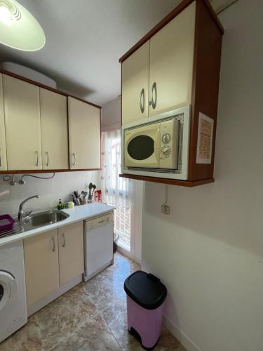 una cocina con fregadero y microondas en Apartamento Beatriz, en Cuenca