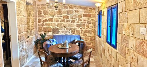 a table and chairs in a room with a stone wall at Stylish apartment with private parking by the marina in ‘Akko