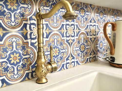 a bathroom with a brass faucet and a sink at Stylish apartment with private parking by the marina in ‘Akko