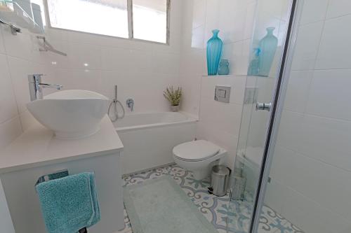 a white bathroom with a sink and a toilet at Ocean-Song in Strand