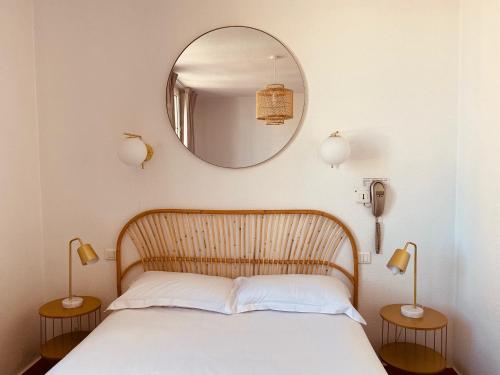 a bedroom with a bed with a mirror and two lamps at Hôtel Le Britannic - centre gare- in Saint Malo