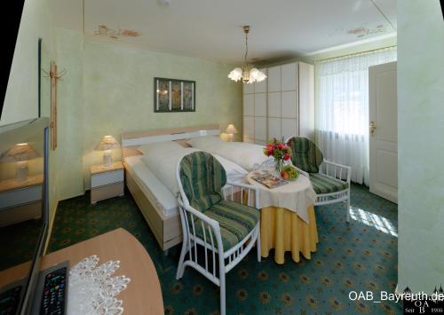 ゲスヴァインシュタインにあるHotel Garni Reginaのベッドとテーブルと椅子のあるホテルの部屋