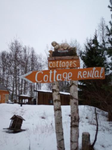 un cartello stradale nella neve accanto a una casa di Verlan Satumaa a Verla