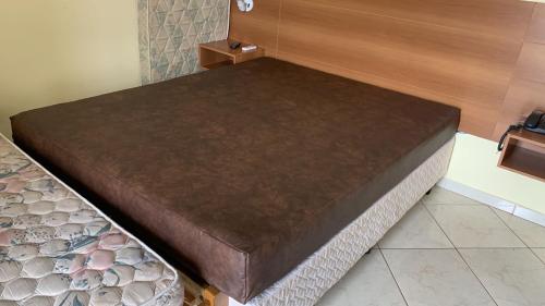 a brown bed in a room with a wooden wall at Thermas Place in Caldas Novas