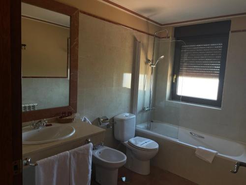 a bathroom with a sink and a toilet and a bath tub at Hotel Garabatos in Navarredonda de Gredos