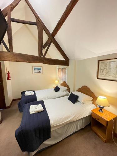 een slaapkamer met 2 bedden en een tafel met een lamp bij Halfway House Inn & Cottages in Bridgnorth