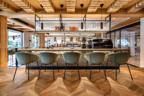 a kitchen with a bar with green chairs at Hotel Pirchnerhof in Reith im Alpbachtal
