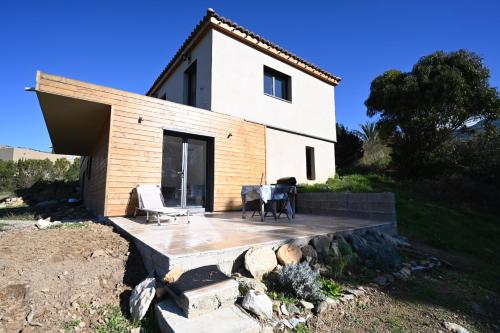 Casa blanca pequeña con mesa y sillas en Charmant appartement F2 neuf Patrimonio, en Patrimonio