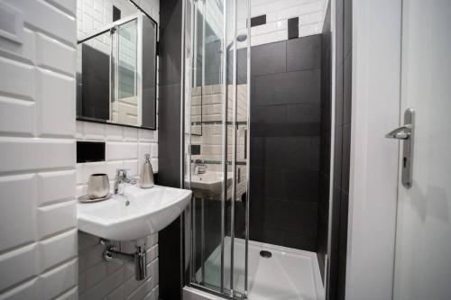 a bathroom with a sink and a glass shower at Alton Aleje Apartment 3 in Warsaw