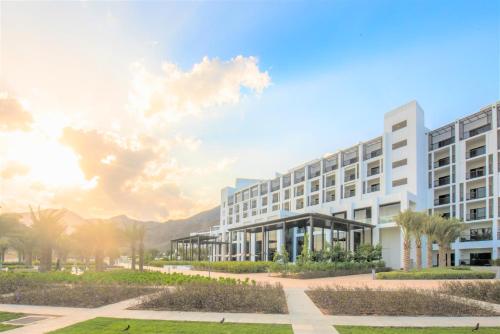 InterContinental Fujairah Resort, an IHG Hotel في العقة: بناء امامه عماره فيها نخيل