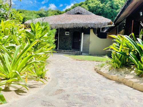 a house with a thatched roof and a pathway at Villa Chez Batista in Takamaka