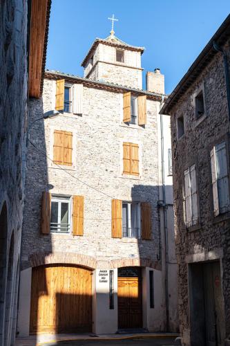 an old stone building with wooden doors and a tower at Chambre Lyre Maison de L'Église du Couvent in Narbonne