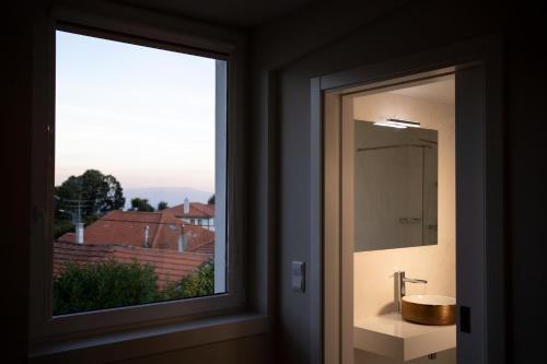a bathroom with a window with a sink and a mirror at Beecaramulo-Apiturismo in Caramulo