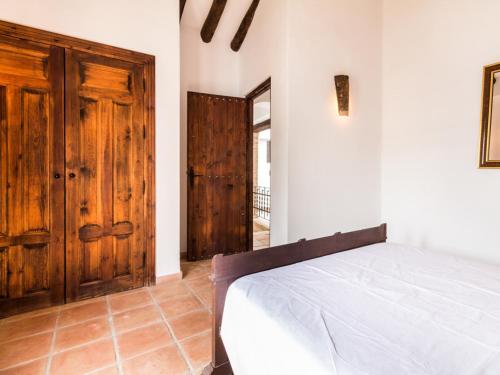 a bedroom with a bed and a wooden door at Casa dos tinajas in Pinos del Valle