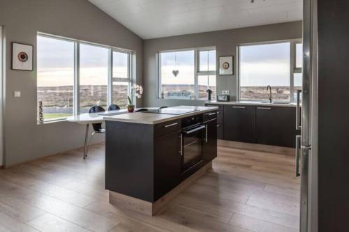 a kitchen with black cabinets and a table and windows at Beautiful house in the nature of West Iceland in Borgarnes