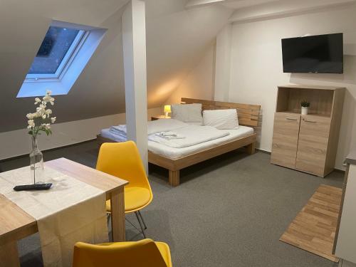 Cette chambre comprend un lit et une table avec des chaises jaunes. dans l'établissement Mikulov Inn - Apartments Slunce, à Mikulov