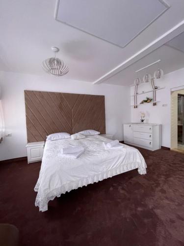 a white bedroom with a large bed with a large headboard at ApartElim in Mănăstirea Humorului