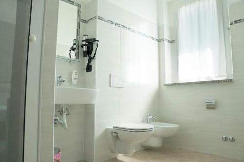 a white bathroom with a toilet and a sink at Hotel Pone in Sesto San Giovanni