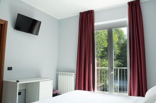 1 dormitorio con una gran ventana con cortinas rojas en Hotel Pone, en Sesto San Giovanni